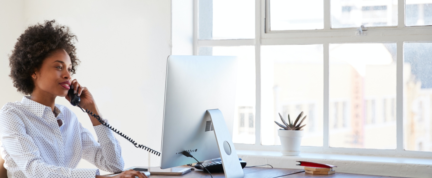 Businesswoman on a telephone at her desk looking at a computer